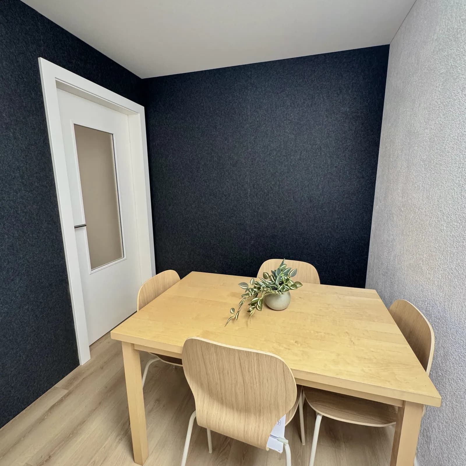 Quiet room Otium :petite salle insonorisée aux murs sombres avec table en bois pour appels visio